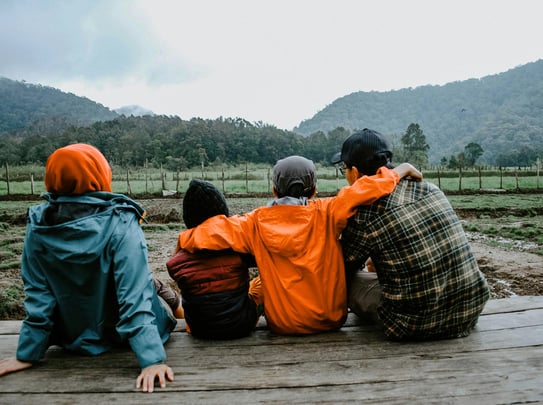 Four people sitting with their backs to us enjoying the view