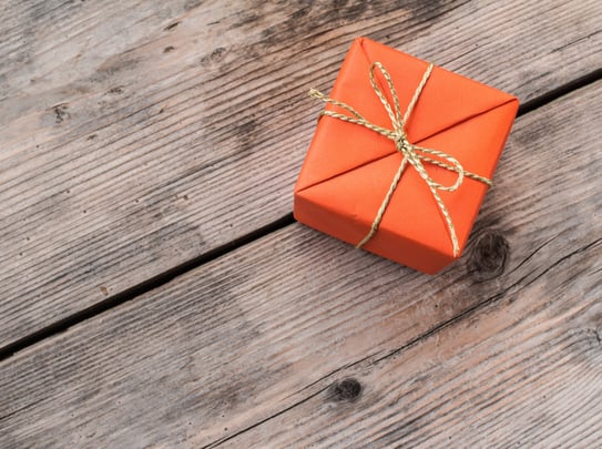 Orange Gift Box and Yellow Ribbon on Wood Background