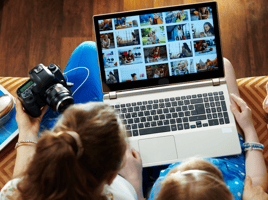 Two women sat with a laptop and a camera looking at photos