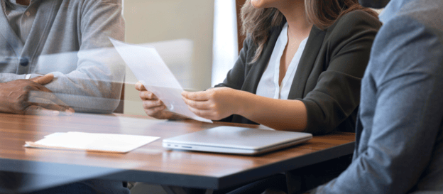 Three people sat around a table reviewing a document