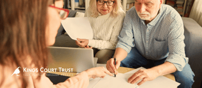 An older couple looking through paperwork with an adviser