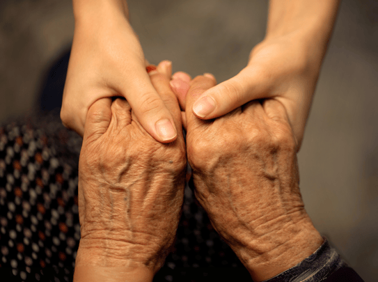 Older person holding hands with younger person