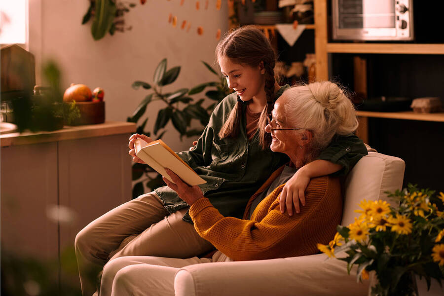 Grandmother and granddaughter reading in armchair