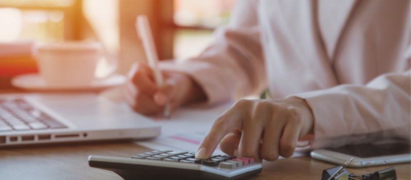 Business woman using calculator and filling out forms.