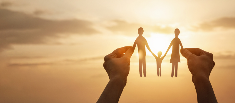 Hands holding a paper cutout of a family