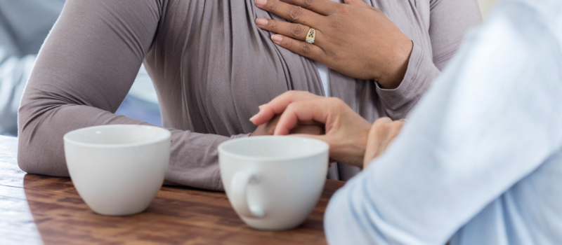 Two people talking at a table with mugs