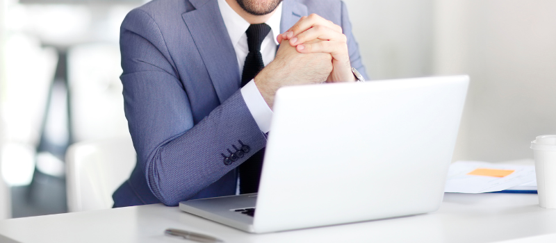 Man in suit sitting at a table with a laptop