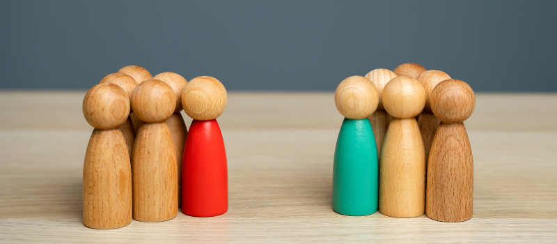 Wooden figures in different colours opposite each other on a table.